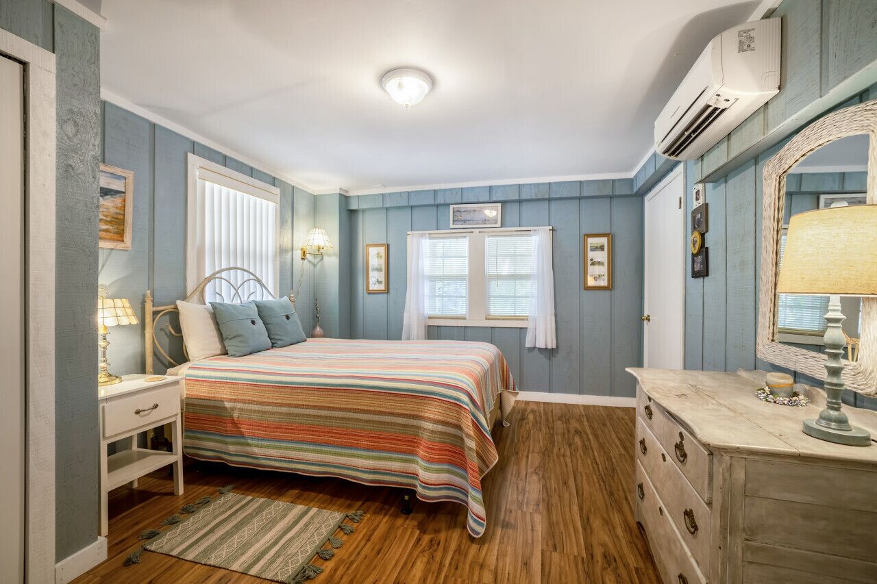 A bedroom with a bed, dresser, and a large mirror.