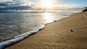 A beach with a clear sky and sunlight reflecting on the sand.