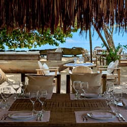 Enjoy a meal under a shaded thatched roof with ocean views.