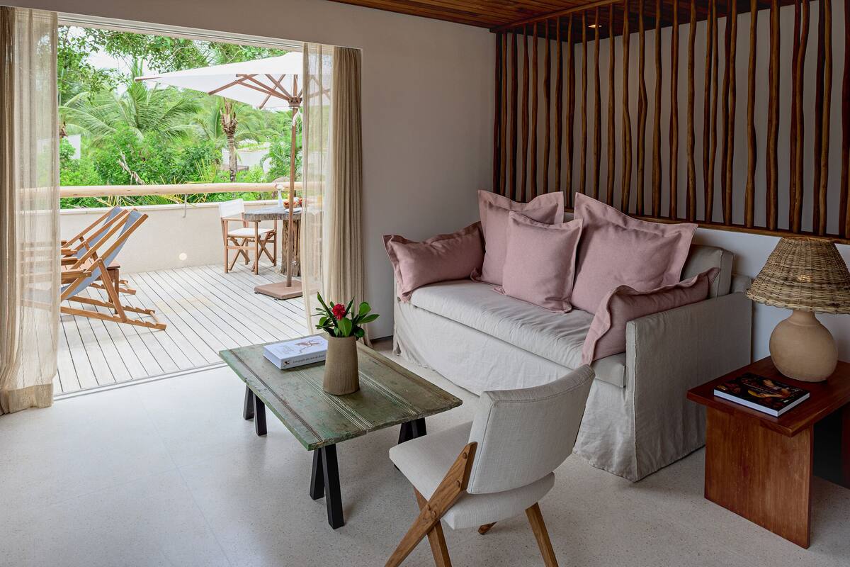 A modern living room with a sofa, a coffee table, and a view of the outdoors.