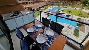 A balcony with a table set for four, overlooking a swimming pool and resort buildings. - Eco Resort Praia dos Carneiros (Tamandaré)