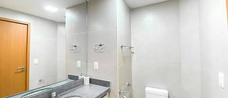 Un baño con lavamanos, espejo, inodoro y ducha.