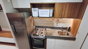 A compact kitchen with a built-in microwave, a stove, and a refrigerator.