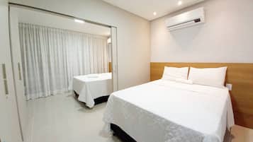 Hotelkamer met een groot bed, een kleiner bed, een spiegel, een airconditioning en een deur met gordijnen.