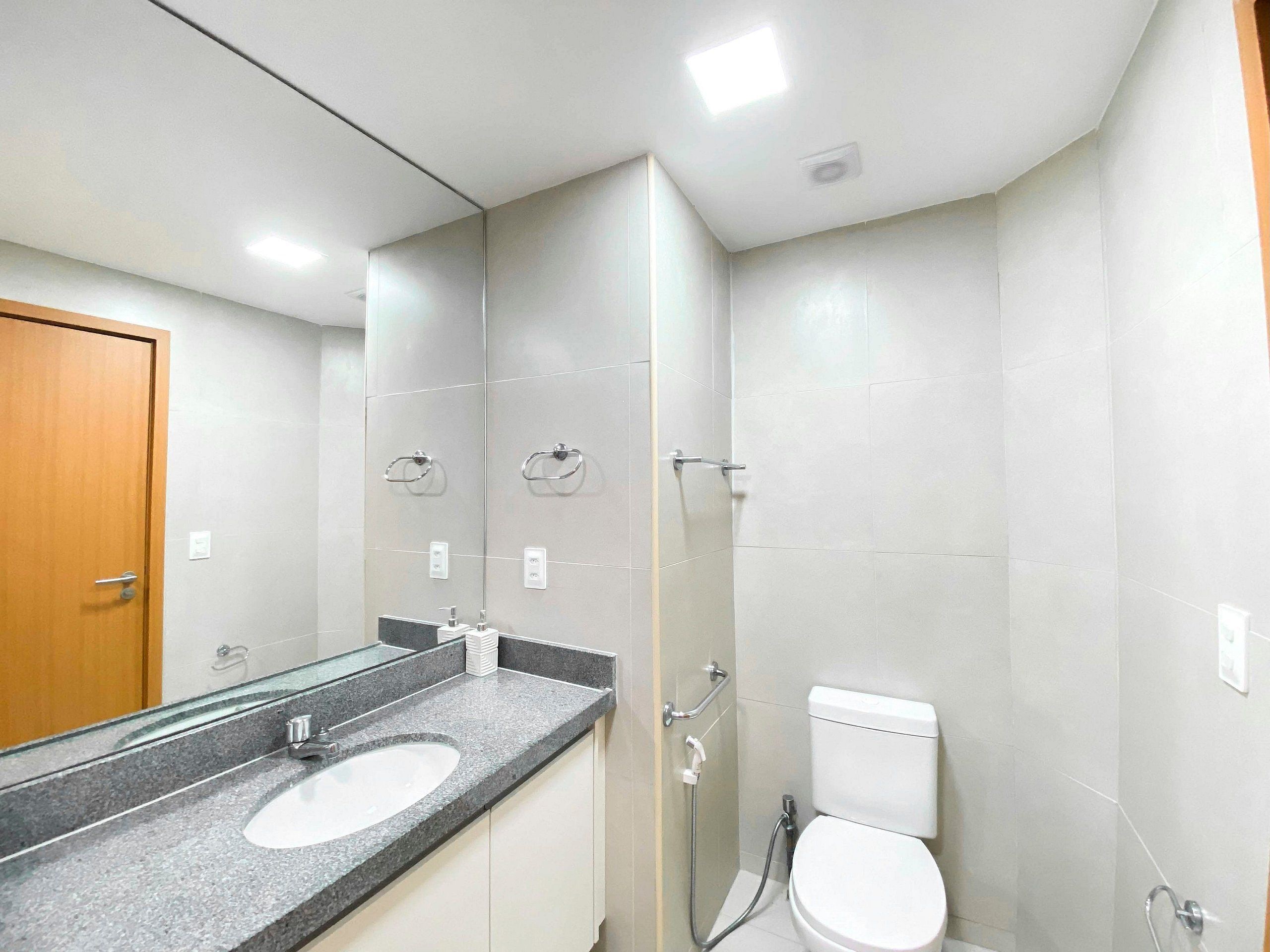 Un baño con lavamanos, espejo, inodoro y ducha.