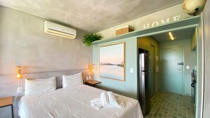 A hotel room with a bed, an air conditioner, a wall-mounted picture, a door, and a tiled floor. - Eco Resort Praia dos Carneiros (Tamandaré)