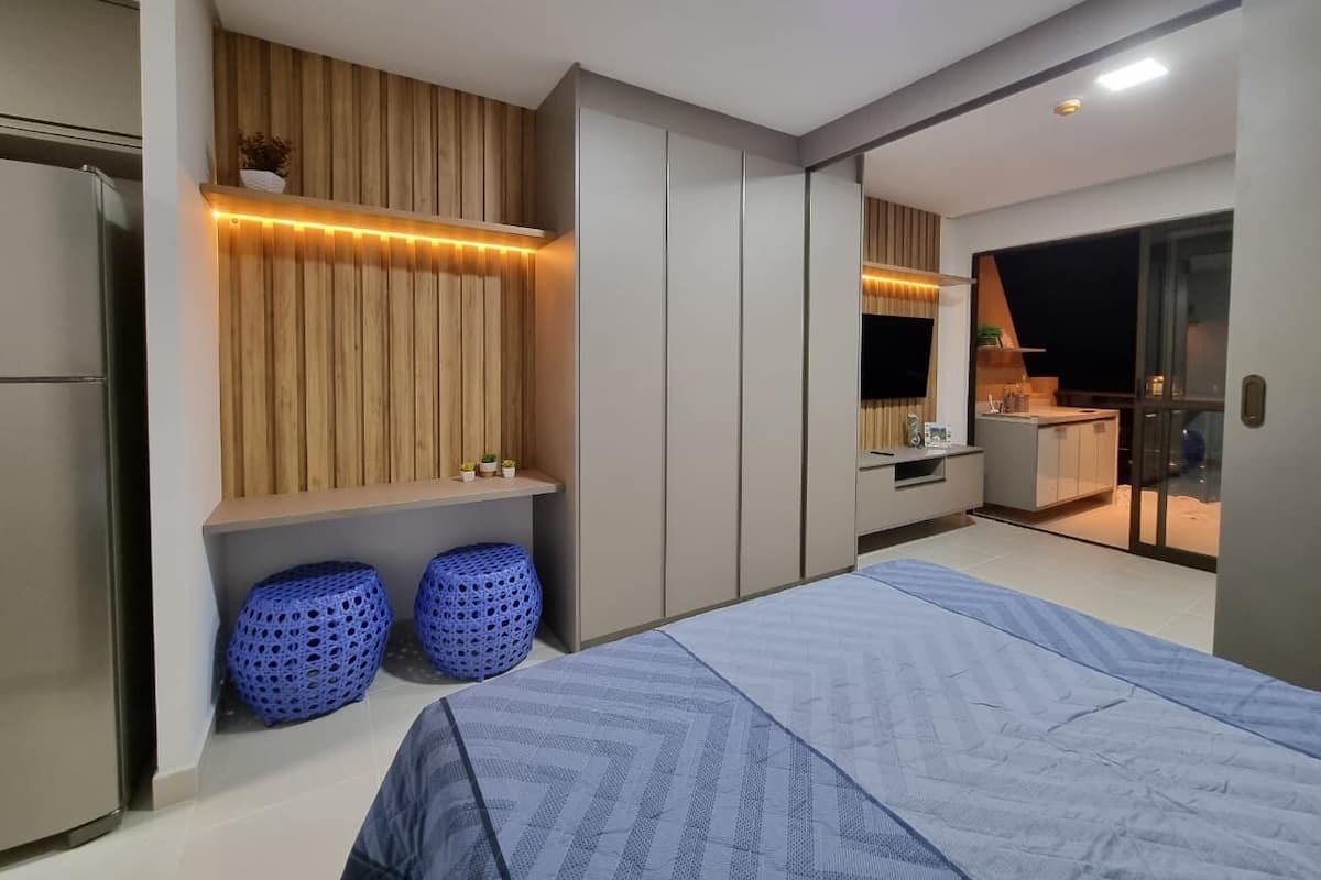 Un dormitorio moderno con cama, armario y una pequeña kitchenette.