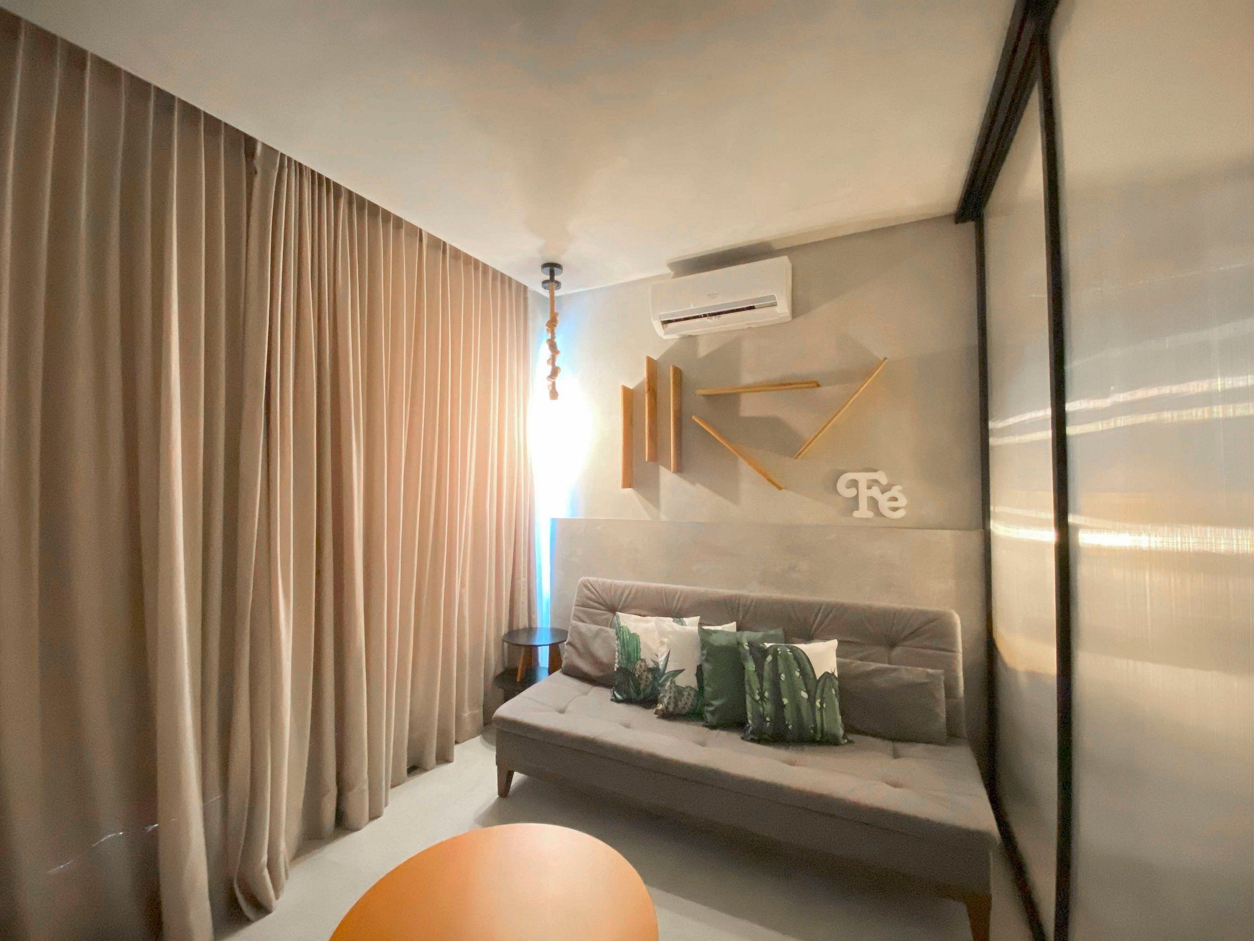 A modern living room with a sofa, a round orange table, and a wall-mounted air conditioner.