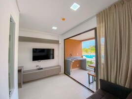 Una sala de estar moderna con un televisor de pantalla plana, un banco empotrado y vista a una piscina al aire libre.