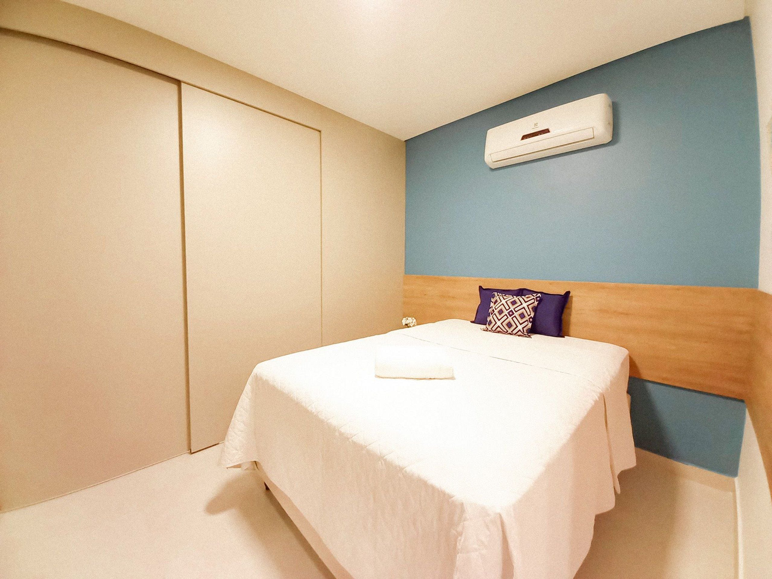 A bedroom with a bed, a wardrobe, and an air conditioning unit.