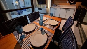 A dining area with a wooden table set for four, black chairs, and blue glassware. - Eco Resort Praia dos Carneiros (Tamandaré)