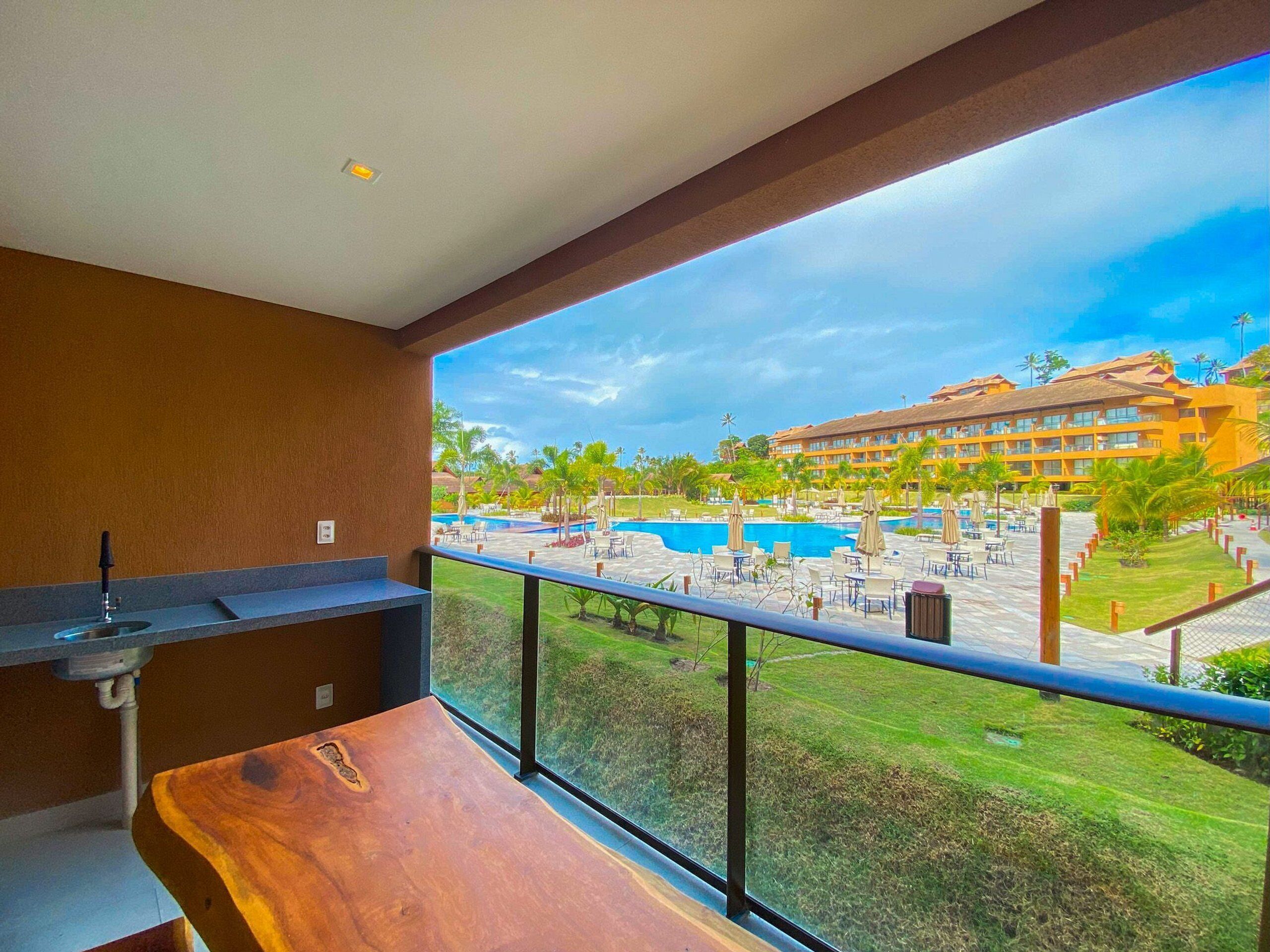 A balcony with a view of a pool and resort buildings.