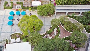 An aerial view of a hotel courtyard with outdoor seating areas, planters, and a curved wooden pathway. - Waikiki Condo - Ocean View - Minutes from the Beach! (Honolulu)