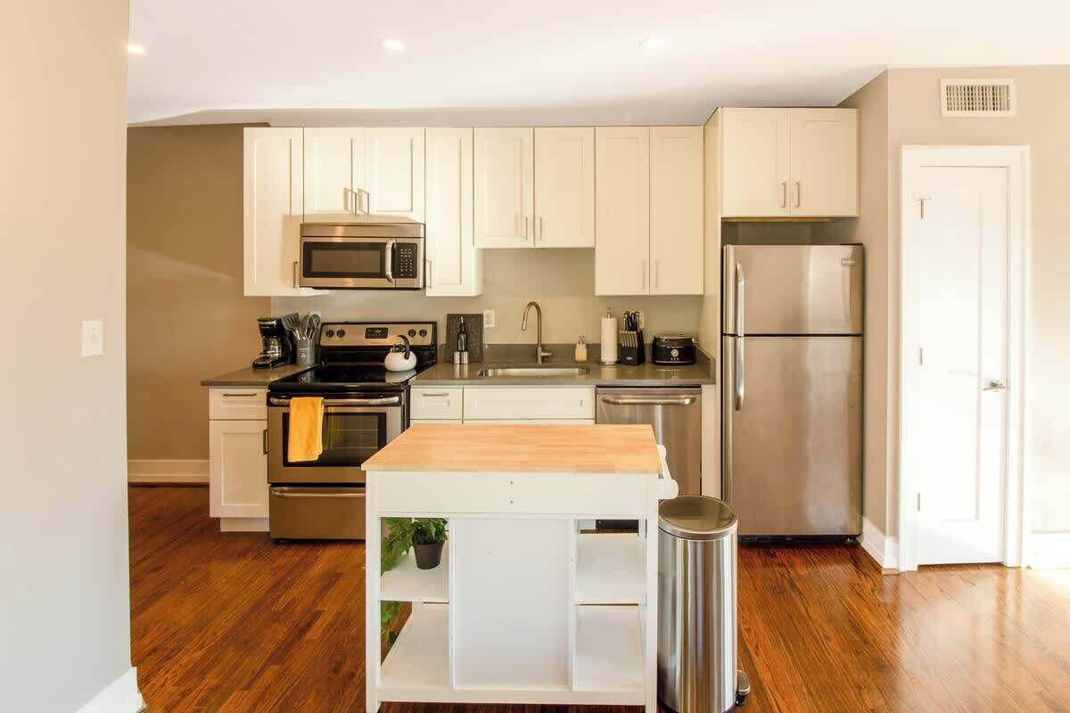 Una cocina moderna con armarios blancos, electrodomésticos de acero inoxidable y encimera de madera.