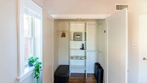 A narrow hallway with a window on the left, a white closet with shelves, and a door on the right. - Chic Minimalist Gem w/ Fenced Backyard + W/D (Saint Louis)