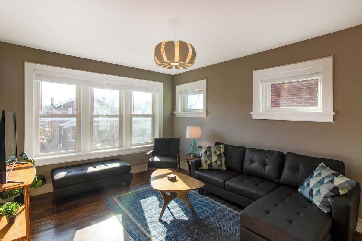 A living room with a sofa, armchair, coffee table, and a television.