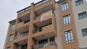 A multi-story building with a sign indicating it is an apartment complex. - Exquisite City Apartments with hot tub (Nairobi)