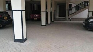 A covered parking area with tiled flooring and columns. - Exquisite City Apartments with hot tub (Nairobi)