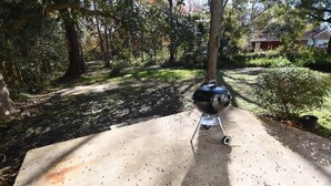 Un patio in cemento con una griglia per barbecue in una zona boschiva.