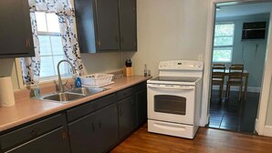 Una cucina con mobili scuri, un piano cottura bianco e un pavimento in legno.