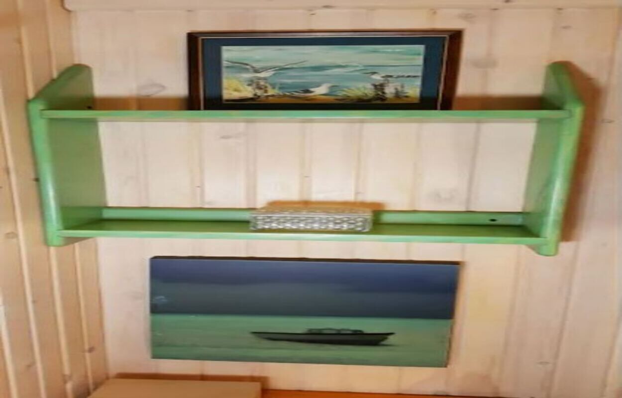 Een houten wand met twee groene planken, elk met een ingelijst foto.