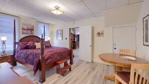 A bedroom with a four-poster bed, a wooden table with chairs, a bedside lamp, and a door leading to another room. -  Stratton House-Unique Historic District Home-Backs to Culp's Hill-Ski Liberty! (Gettysburg)