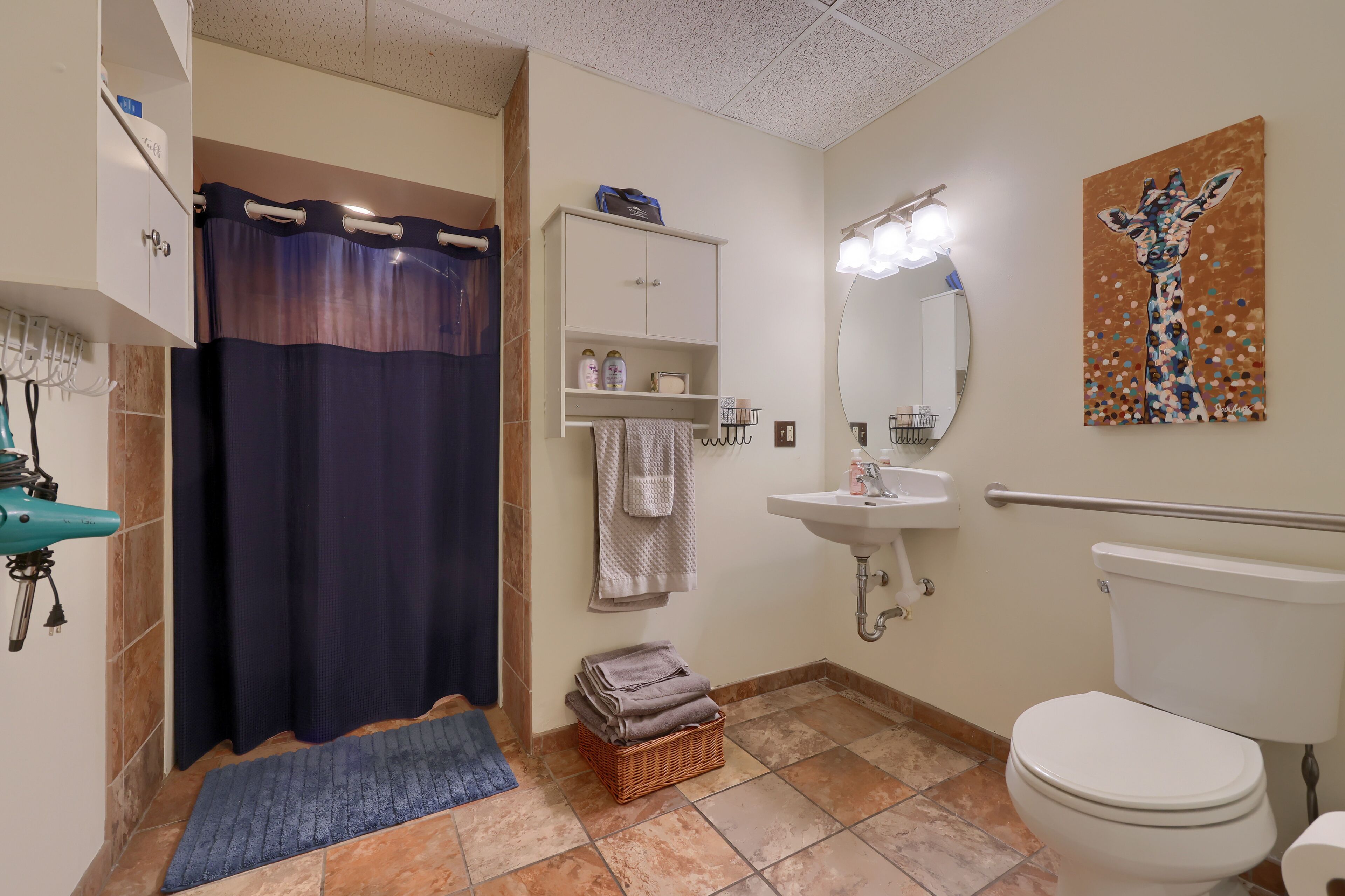 A bathroom with a shower, sink, toilet, and a towel rack.