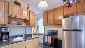 A kitchen with wooden cabinets, a stainless steel refrigerator, a coffee maker, and a stove. -  Stratton House-Unique Historic District Home-Backs to Culp's Hill-Ski Liberty! (Gettysburg)