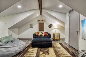 Une chambre avec un lit en mezzanine, un panneau lumineux indiquant « MUSIQUE », un disque et une lampe.