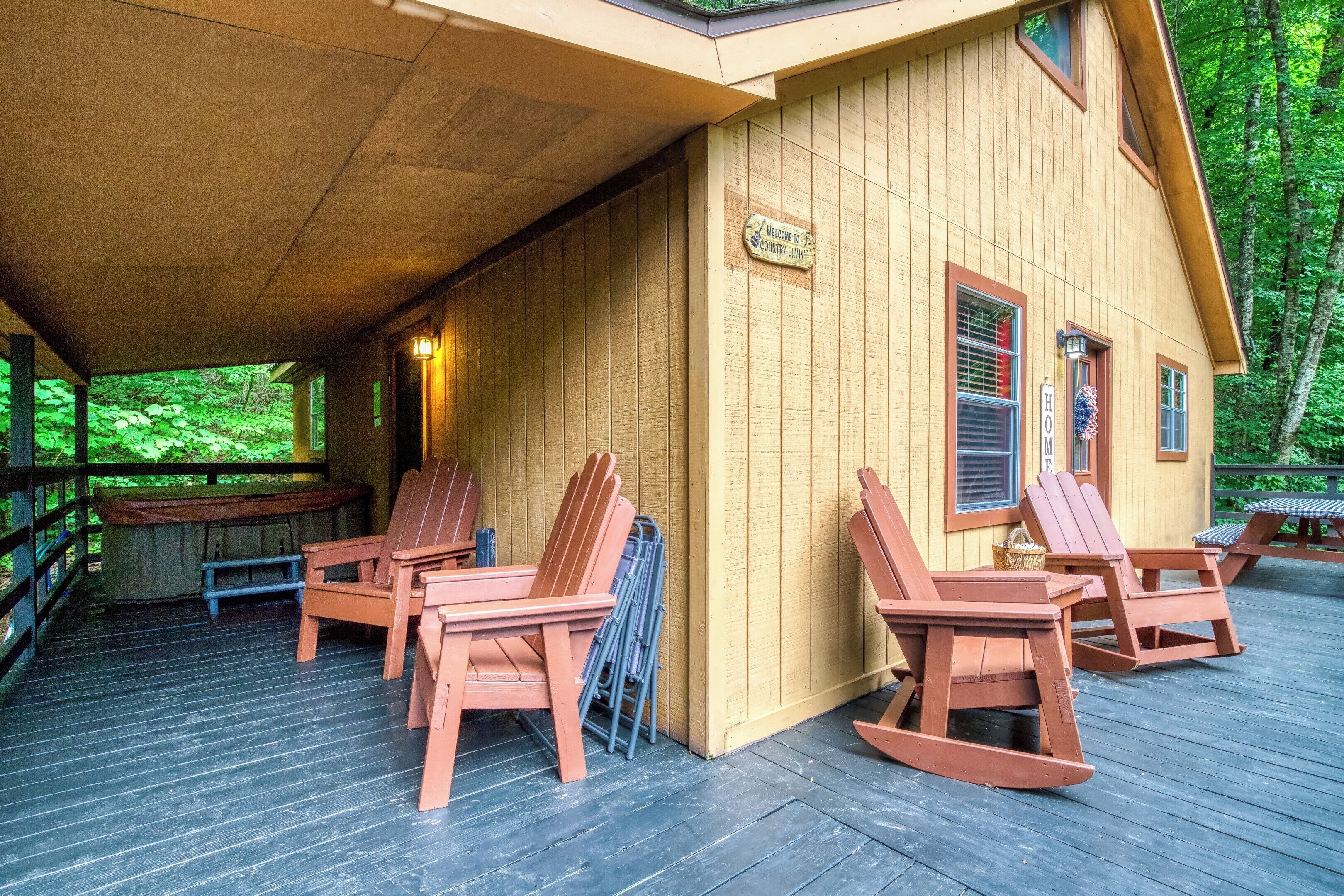 A wooden cabin with a covered porch, rocking chairs, and a sign welcoming guests.