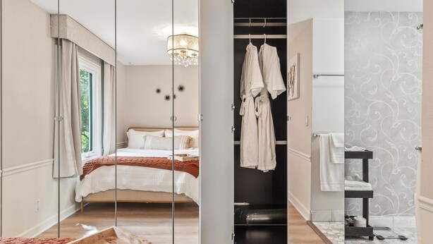 Une chambre à coucher avec un lit, une armoire avec des vêtements suspendus et une salle de bain avec des toilettes et un lavabo.