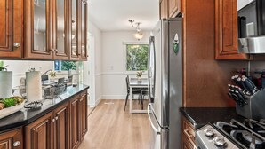 Une cuisine moderne dotée de meubles en bois, d’appareils électroménagers en acier inoxydable et d’un coin repas offrant une vue sur l’extérieur.
