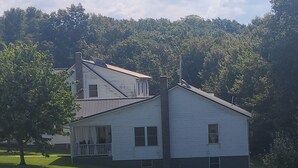 A white house with a porch, surrounded by a grassy field and trees. - The Bunkhouse @Dragonfly Ranch is made to make you feel like home away from home (Cub Run)