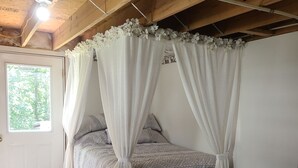 A bedroom with a canopy bed, a white door, and a window with a view of trees. - The Bunkhouse @Dragonfly Ranch is made to make you feel like home away from home (Cub Run)