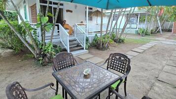 An outdoor patio with a table and chairs, a covered area, and a house in the background.