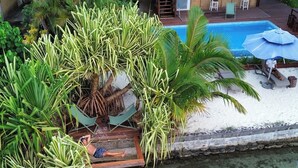 Ein tropisches Resort mit Pool, einer strohgedeckten Struktur und zwei Kajaks.