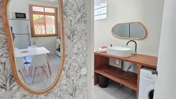 A bathroom with a sink, mirror, and washing machine.