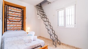 Ein Schlafzimmer mit einem Bett, einem Fenster, einer Treppe und einem Handtuchhalter.
