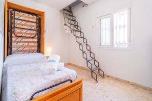 A bedroom with a bed, a window, a staircase, and a towel rack.