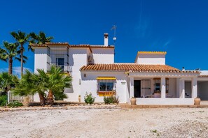 A white building with a tiled roof, a balcony, and a small patio area.