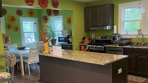 A modern kitchen with green walls, a central island, and wooden flooring.