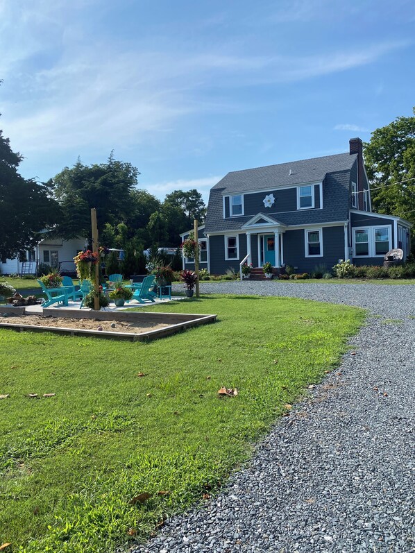 A two-story house with a front porch, a driveway, and a well-maintained lawn. - Minutes to the BEACH! Boat friendly, fire pit, bocci & large yard for famly fun! (Cape Charles)