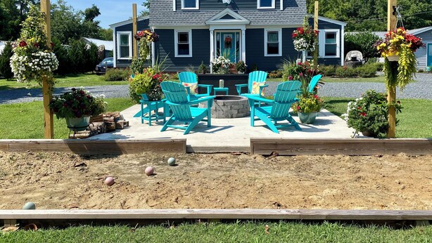 A house with a front porch, a small garden, and a seating area with chairs.