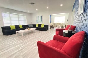 Un salon moderne avec un ensemble de canapés, une table basse et des fauteuils rouges.