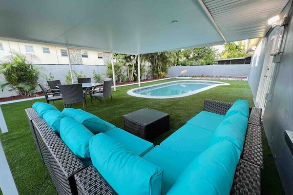 Partially covered backyard with comfortable patio furniture and a pool for those sunny South Florida days