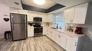 Una cocina moderna con armarios blancos, electrodomésticos de acero inoxidable y suelo de madera.