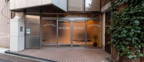 A FUTABA HOTEL entrance with a glass door and a welcome sign.