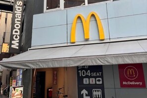 Een McDonald's restaurant met een groot geel logo, een bord dat 104 zitplaatsen aangeeft, en een McDelivery logo.