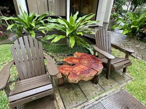 Relax in a serene outdoor space with Adirondack chairs and a rustic wooden table.