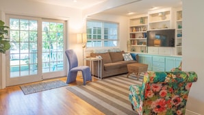 Una sala de estar con sofá, sillón y televisor sobre un mueble.
